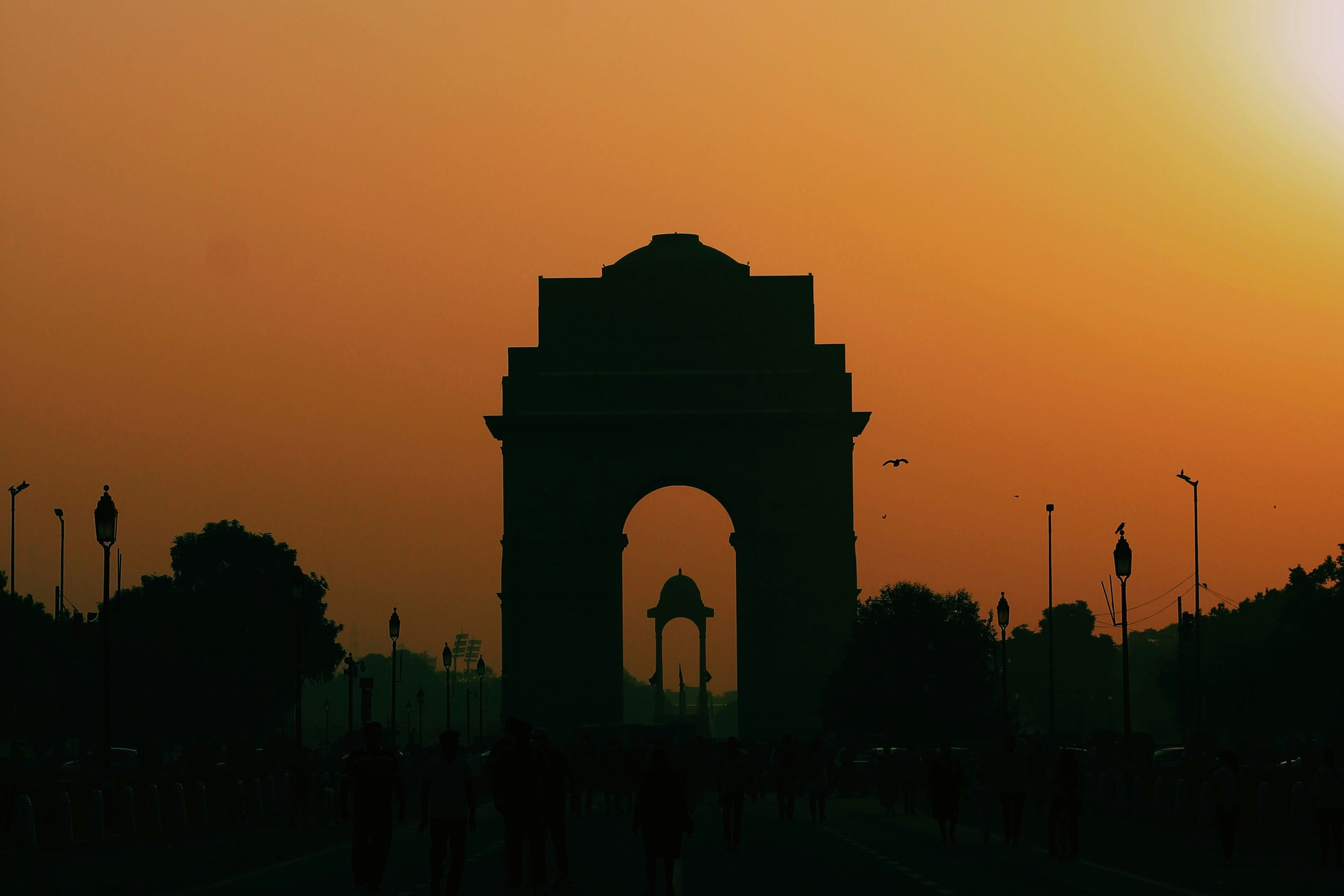 silhouette of people walking on park during sunset near india gate