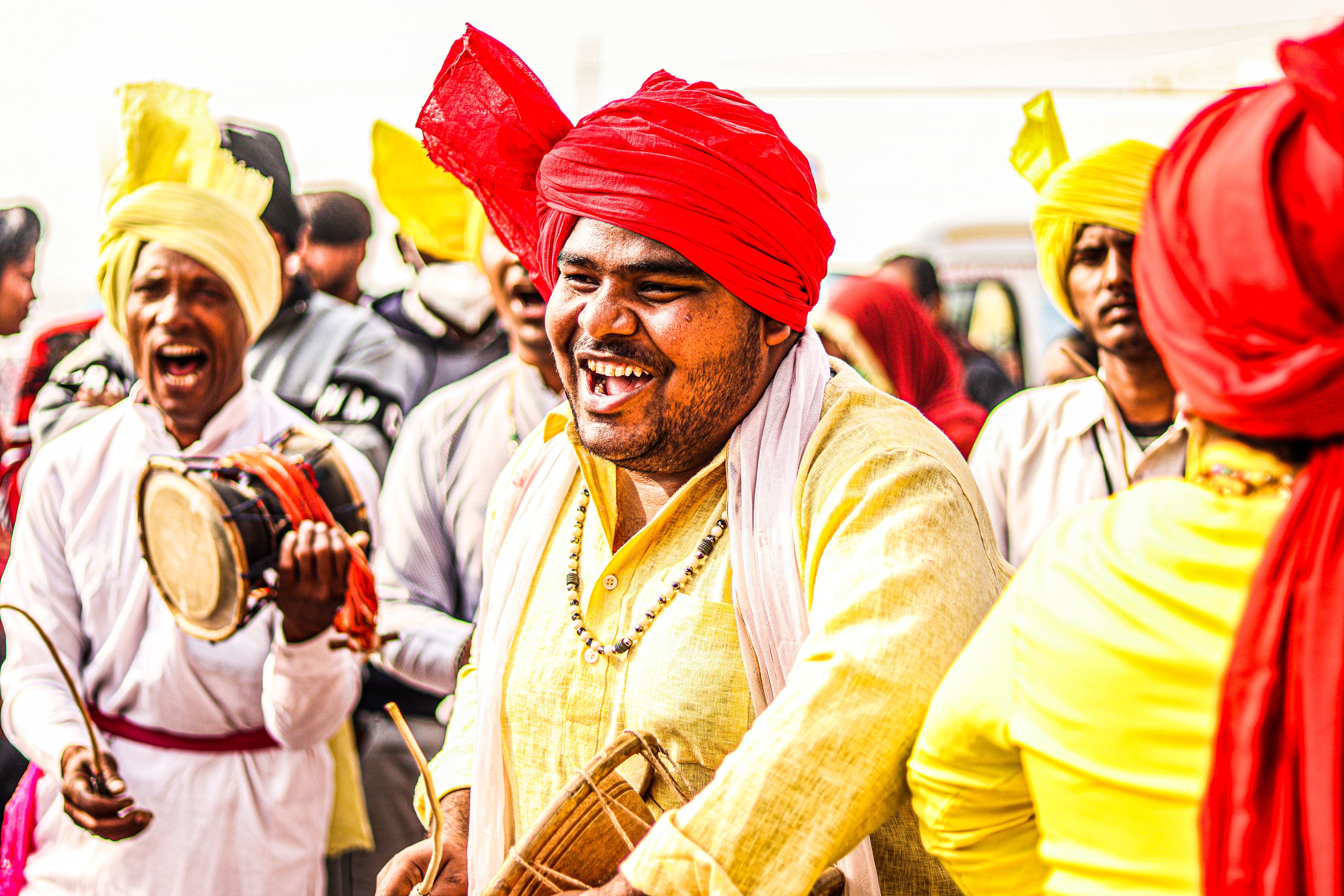 smiling men celebrate at an indian festival with drums and vibrant turbans and traditional attire