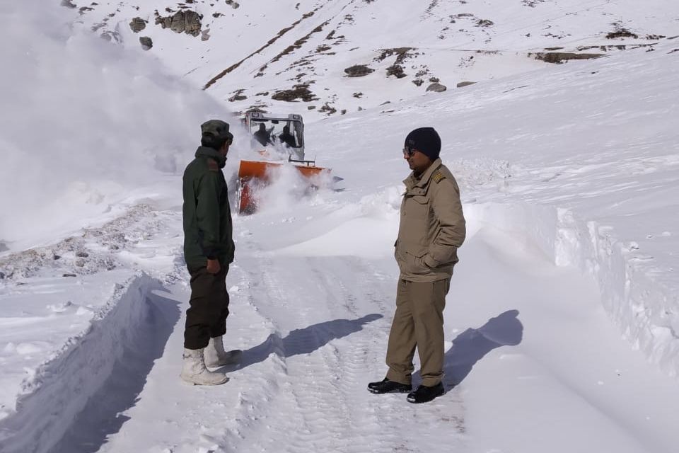 people sanding in front of a machine clearing snow at rohtang pass