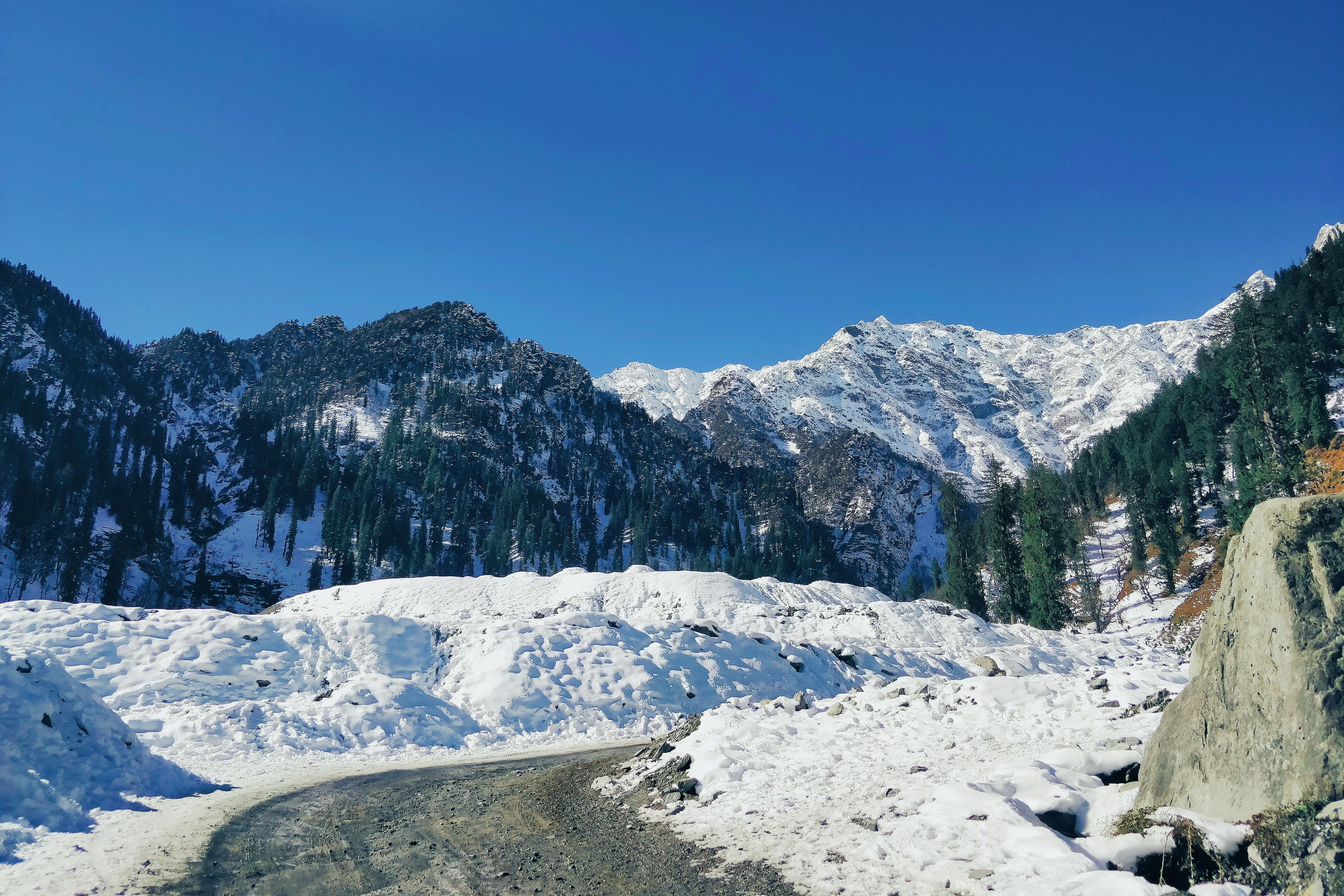 snow covered mountains in himachal pradesh under blue sky during daytime