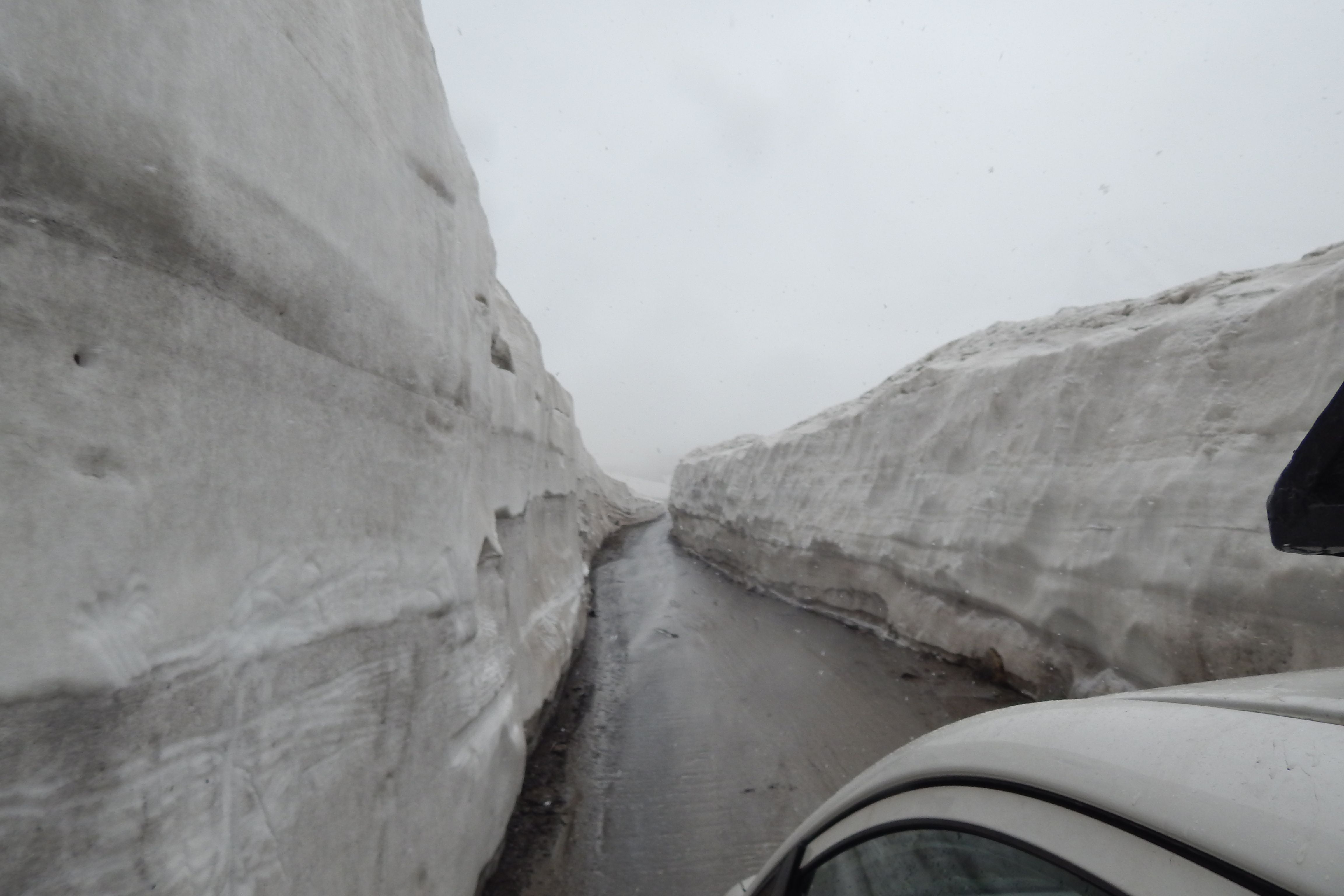 a road passing through rohtang pass with snow on both side