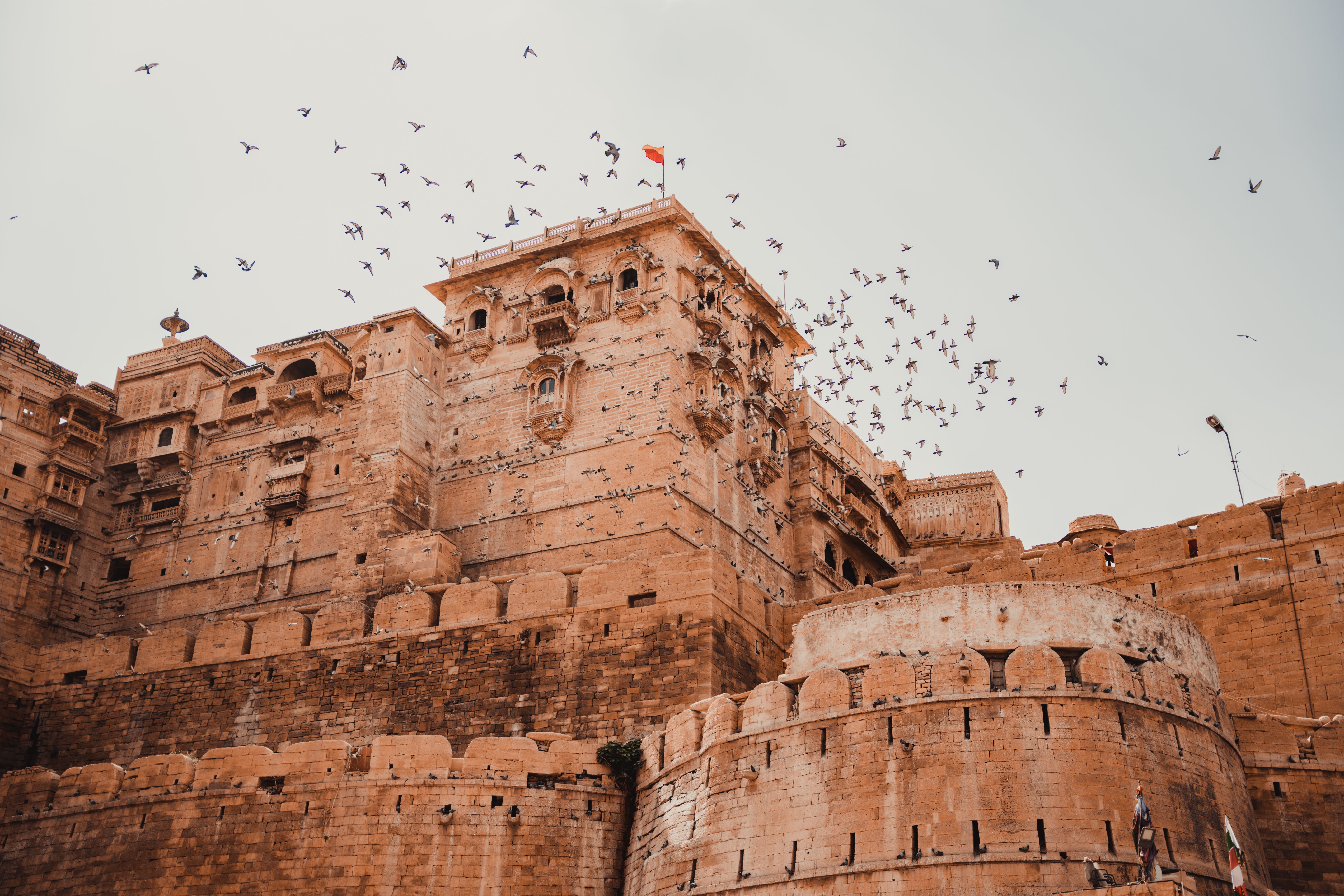 view of jaisalmer fort with birds soaring in the clear sky