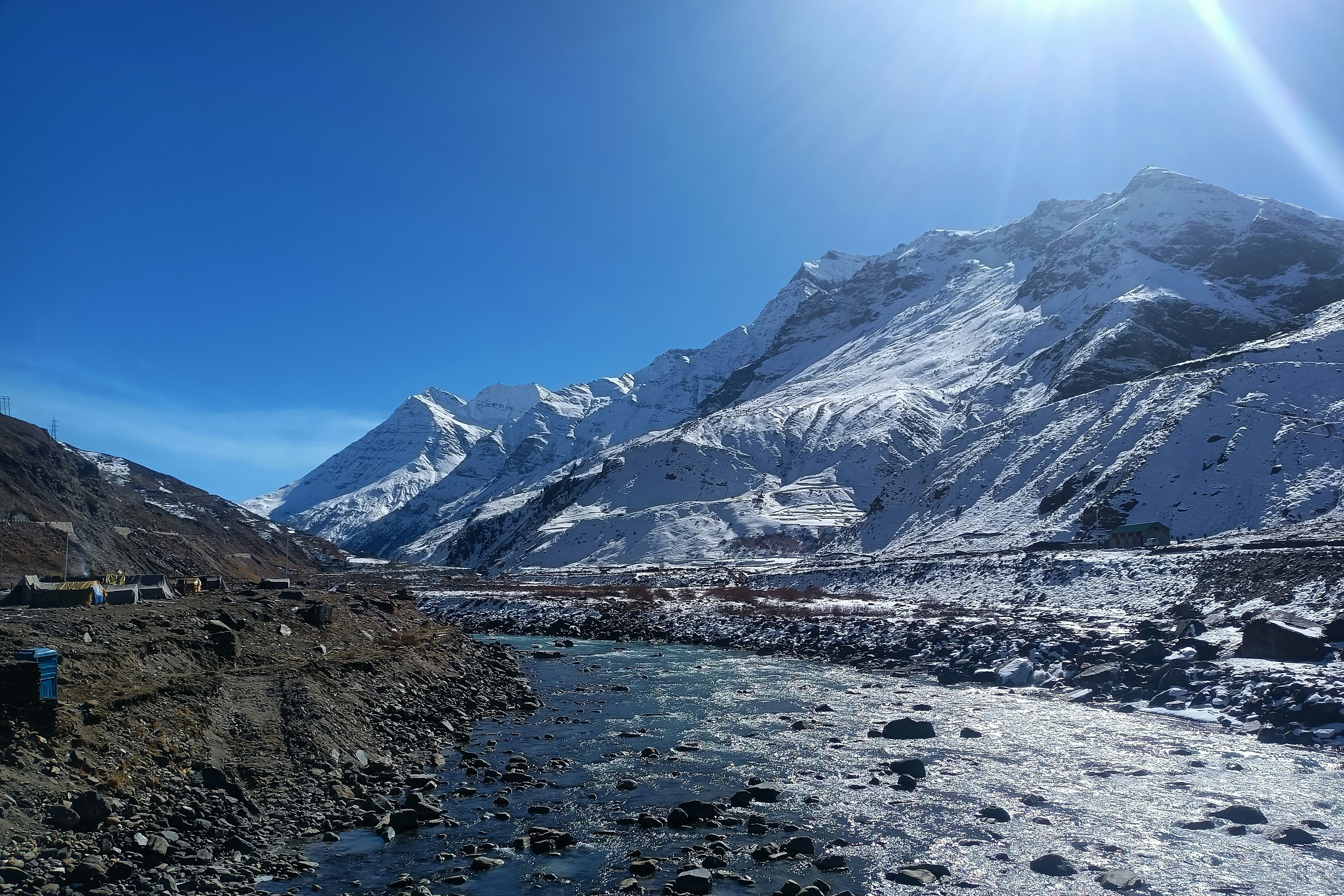 sun shining brightly on the snowy mountains near sissu