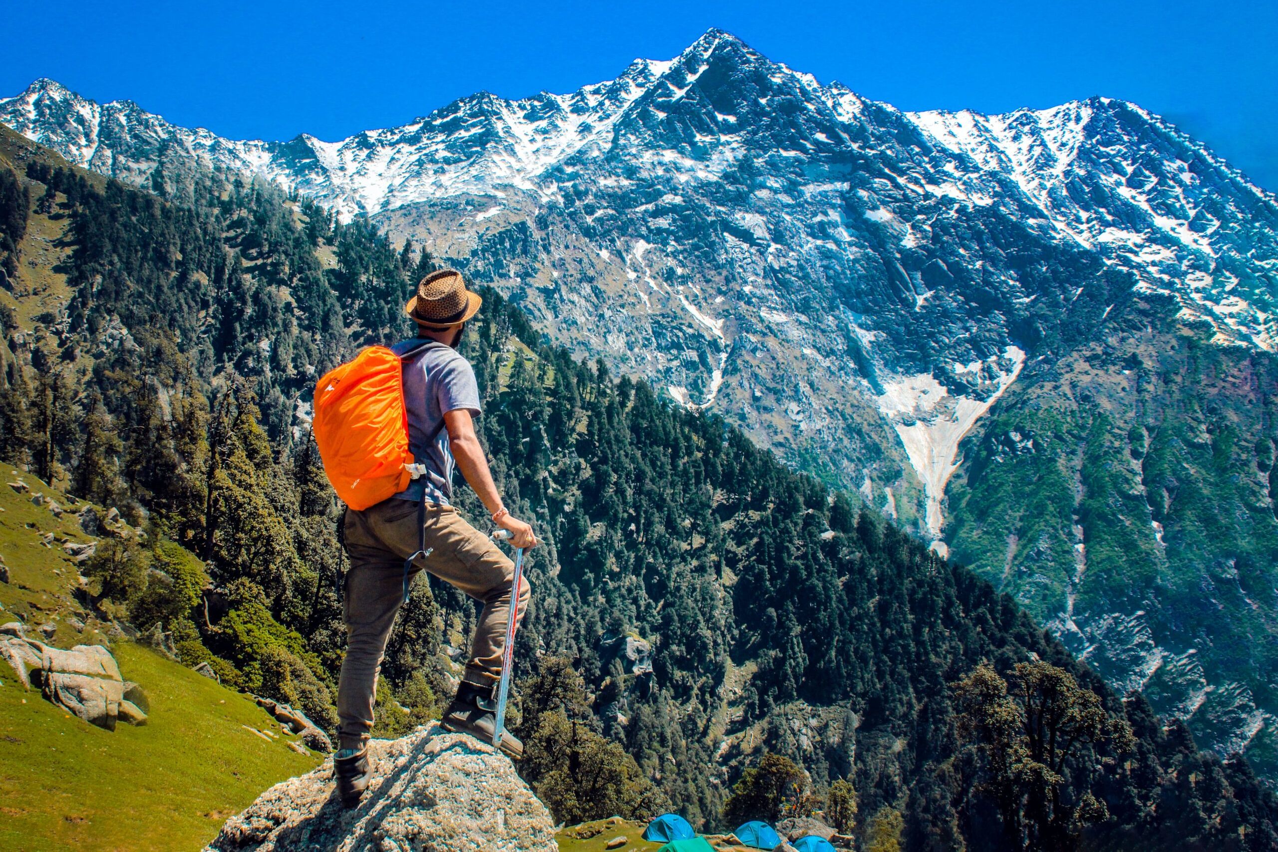 a person standing on a rock with snow covered mountains in the backdrop