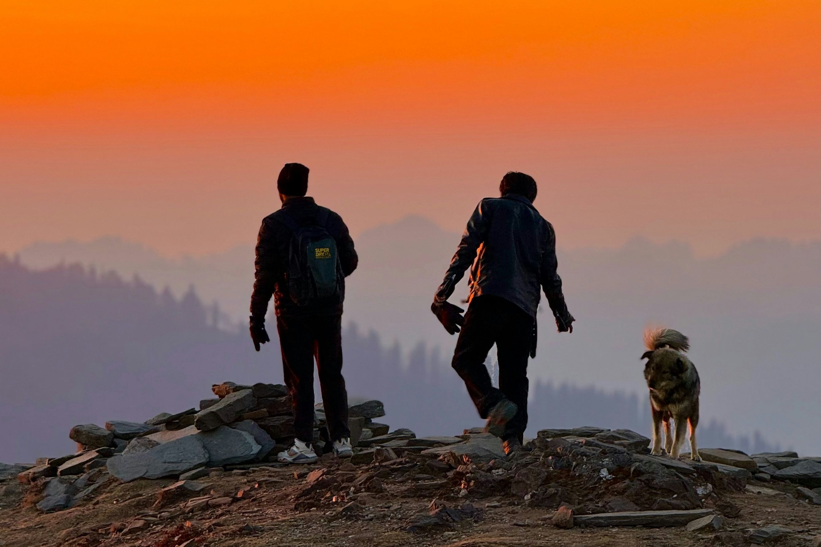 two people standing on top of a mountain near raghupur fort in jibhi