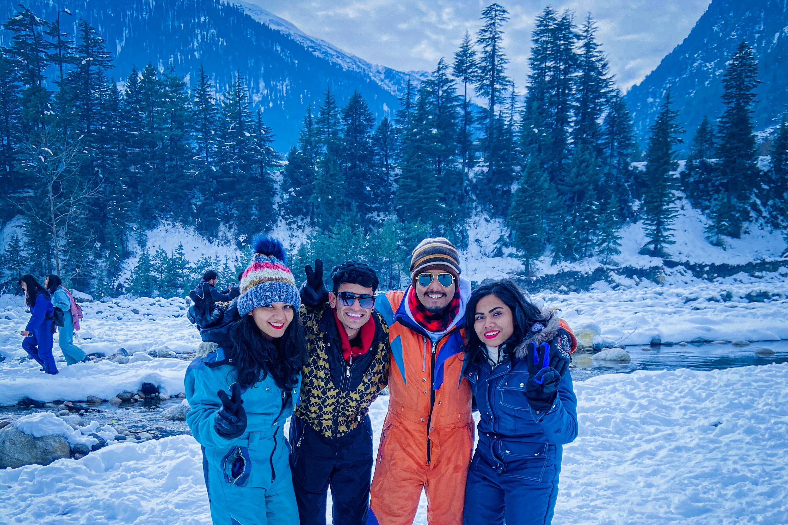 two womean and men standing on snow covered ground during daytime in manali