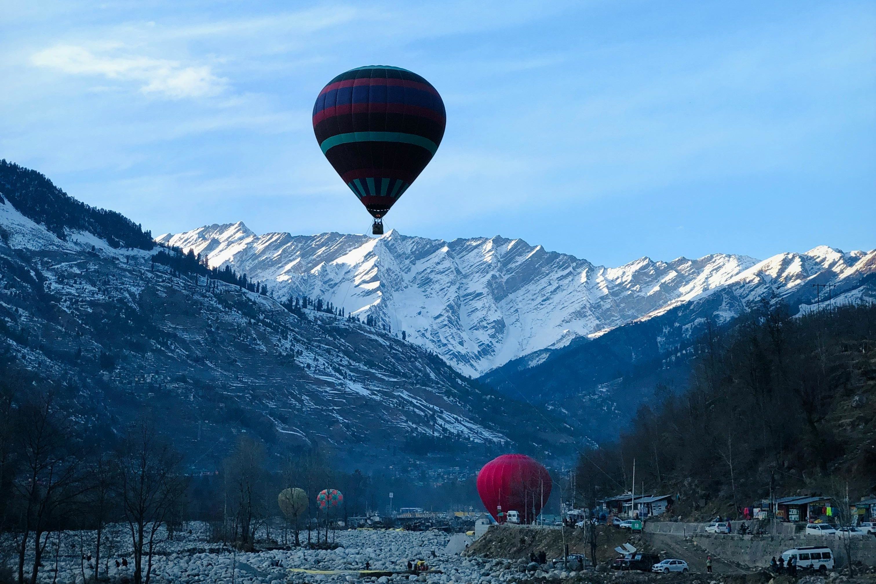 vibrant hot air balloon over snowy mountains near solang valley