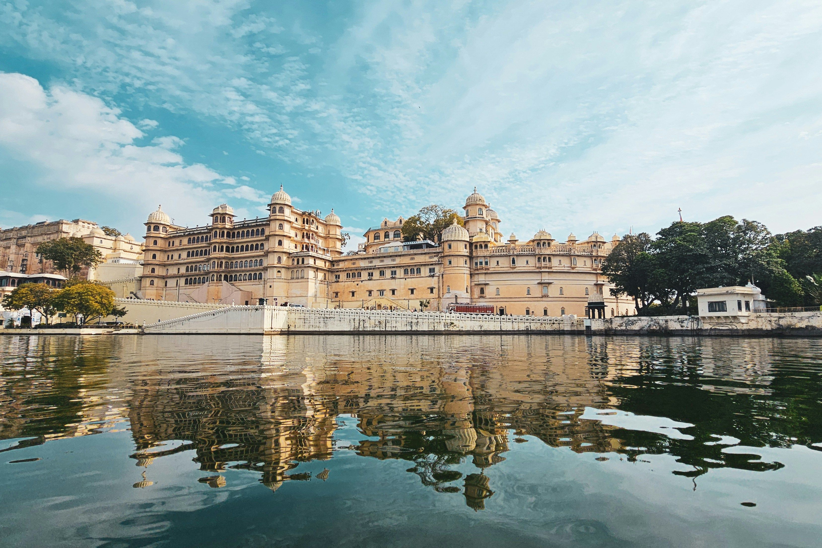 view of city palace in udaipur beside a lake