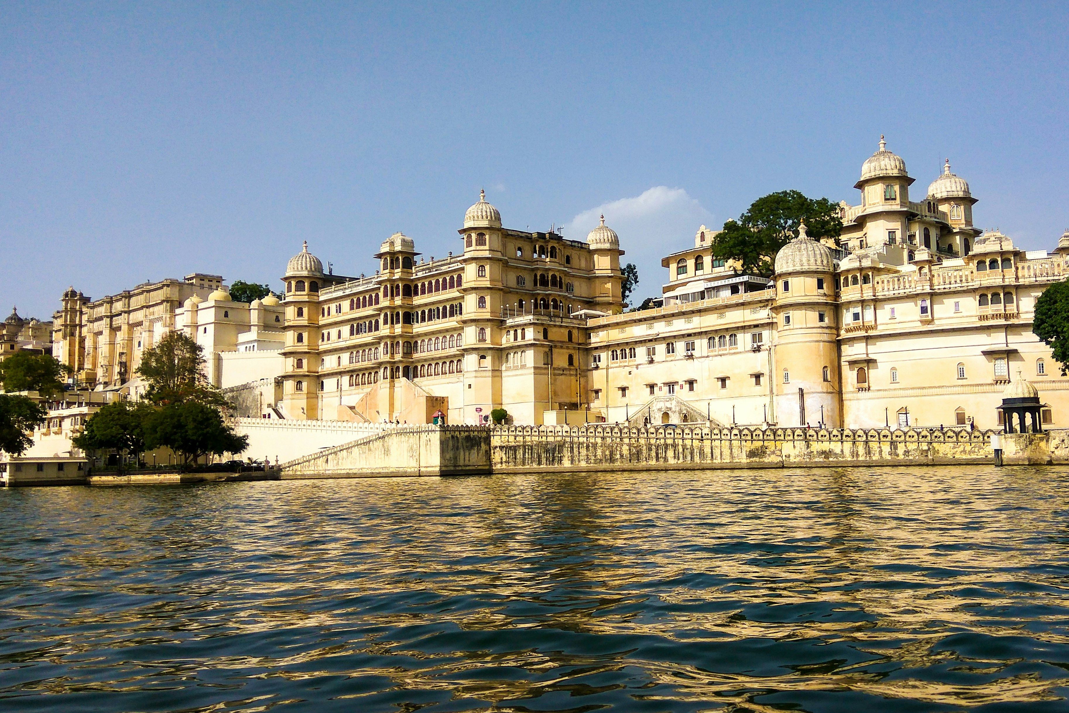 view of city palace in udaipur beside a lake during daytime