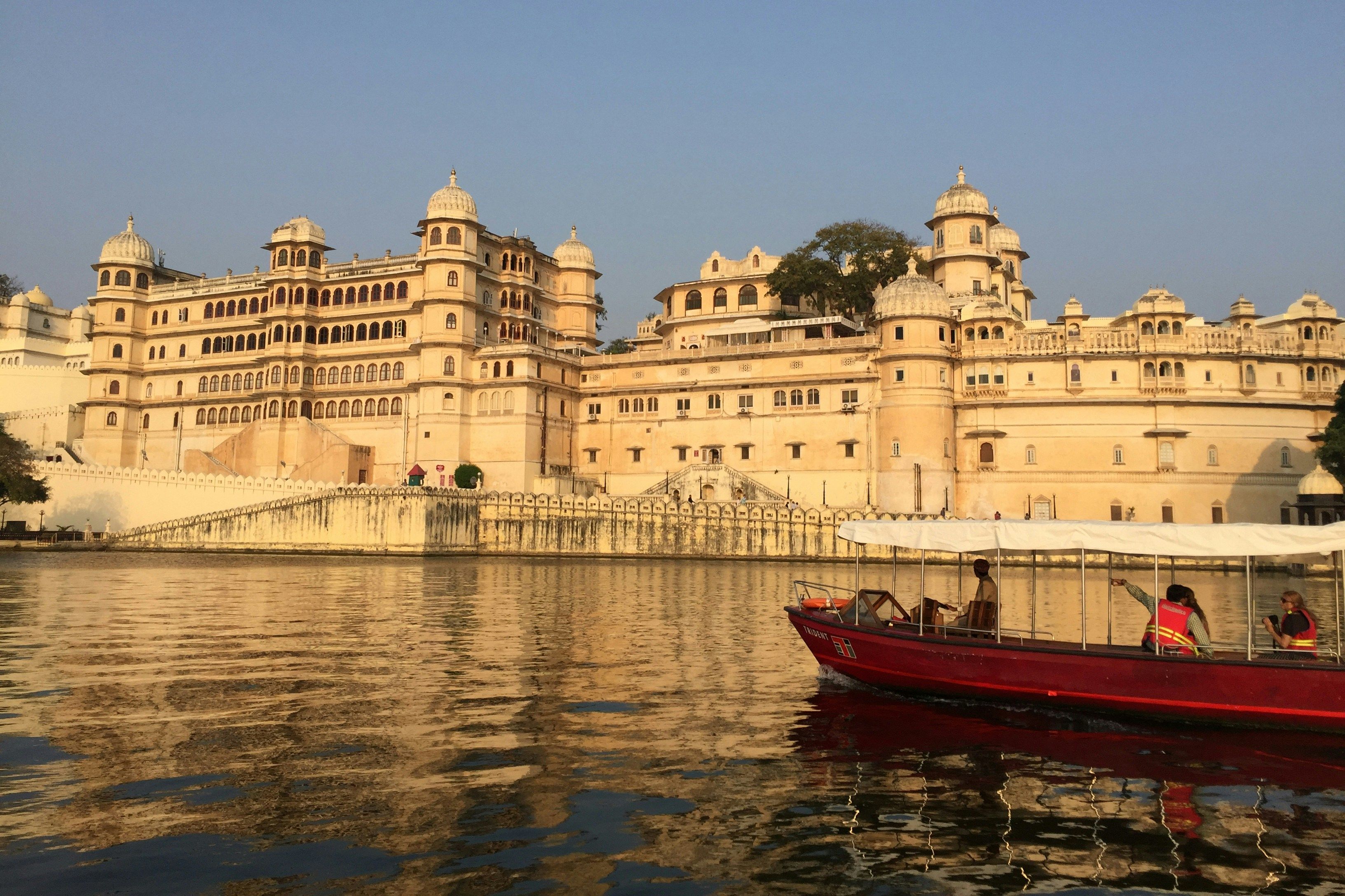 view of city palace in udaipur beside a lake during daytime