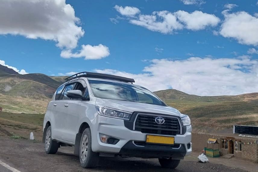 view of innova cab standing on a road in himachal pradesh with mountains in the backdrop