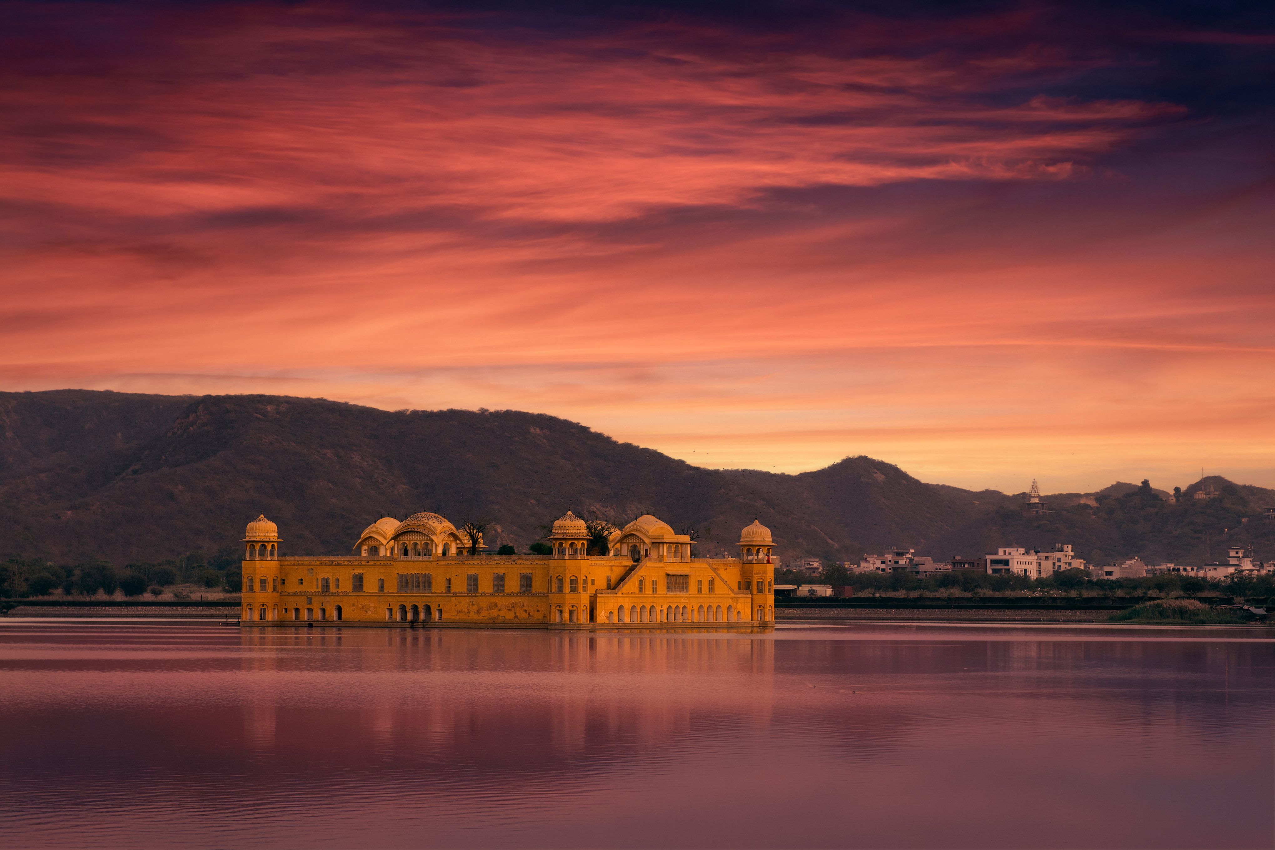 view of the jal mahal palace reflecting on the scerene man sagar lake during sunset in jaipur