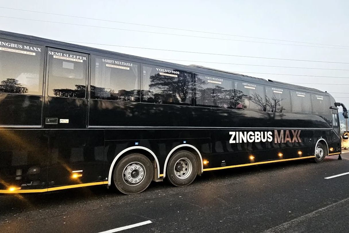 a black volvo bus on road travelling between delhi and manali