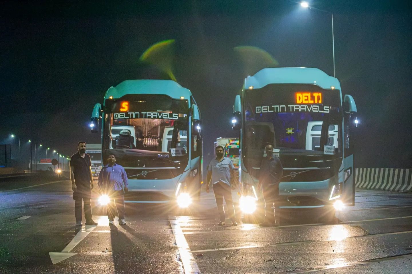 people standing in front of two volvo buses on road travelling between delhi and manali