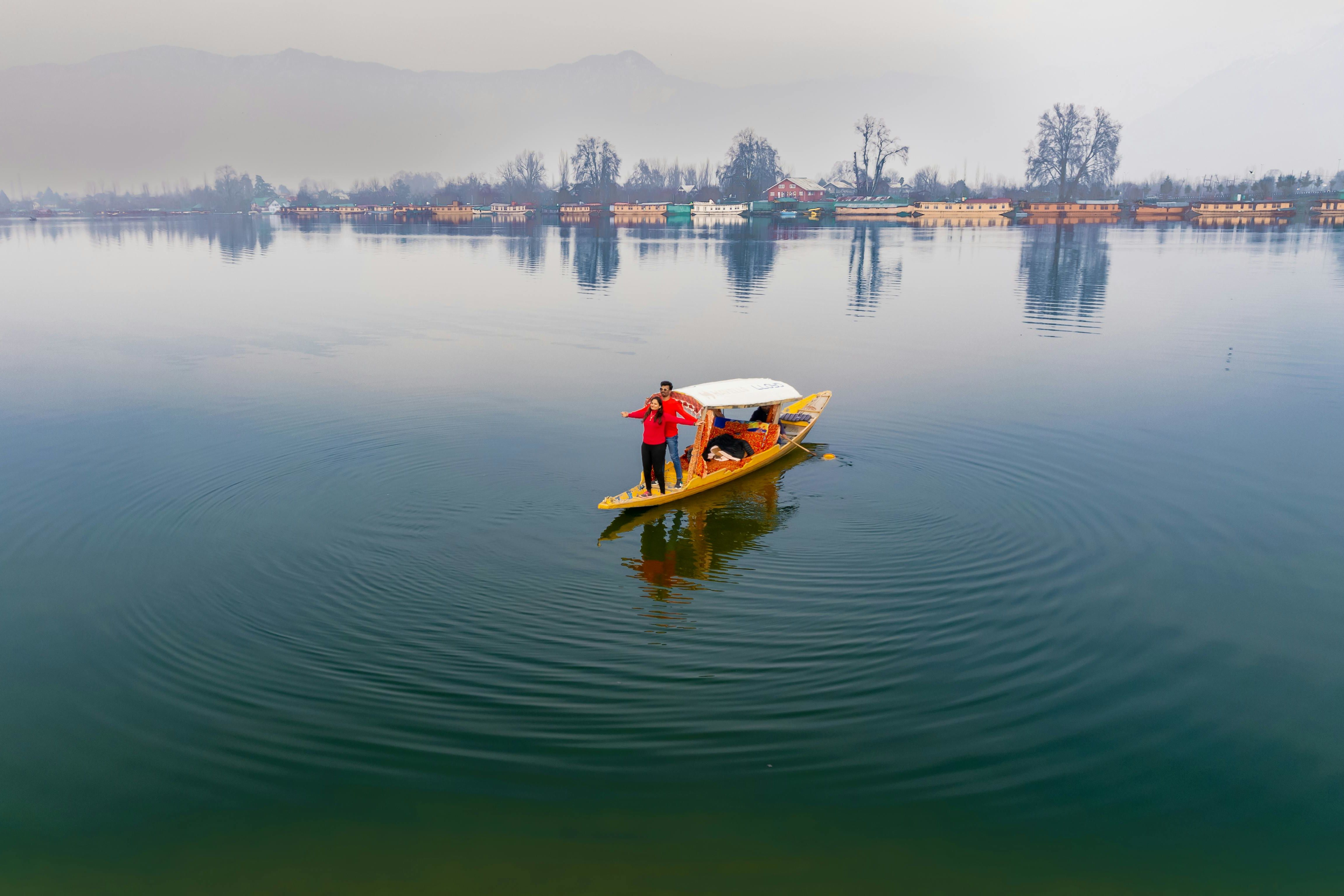 woman and man in red clothing standing on shikara boat in dal lake