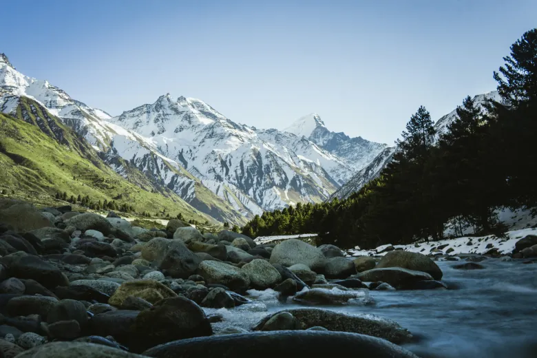 mountains covered with snow and river flowing below it